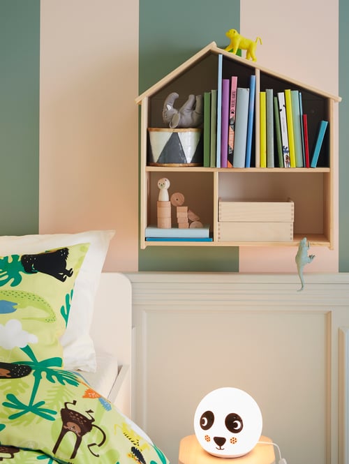 Chambre d’enfant avec linge de lit coloré, lampe de table LED panda et étagère murale en bois en forme de maison de poupée.
