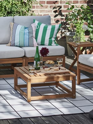 A wooden table has been set up on the balcony, with food and drinks on it.