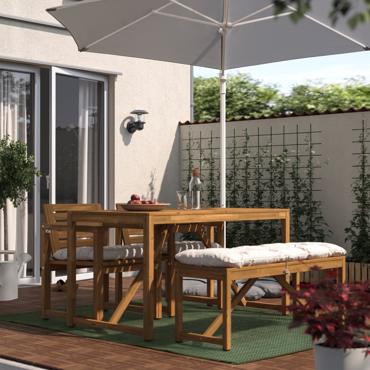 Ein dunkelgrüner MORUM In-/Outdoor Teppich liegt unter einer NÄMMARÖ Sitzgarnitur aus Akazienholz.
