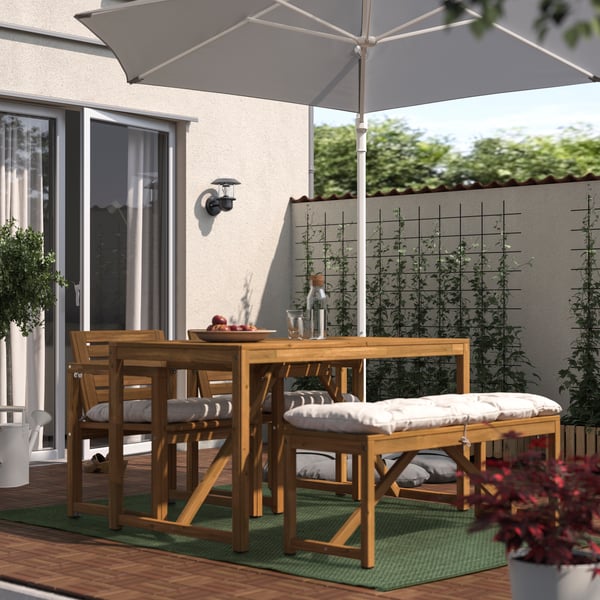 Un comedor de terraza NÄMMARÖ con sillas y banquetas de madera.