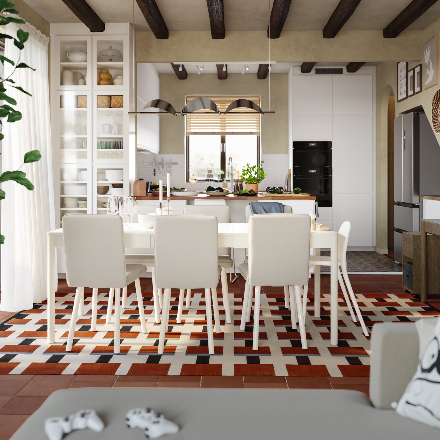 A dining room with a TONSTAD extendable table in off-white has a white kitchen with a peninsula in the background.