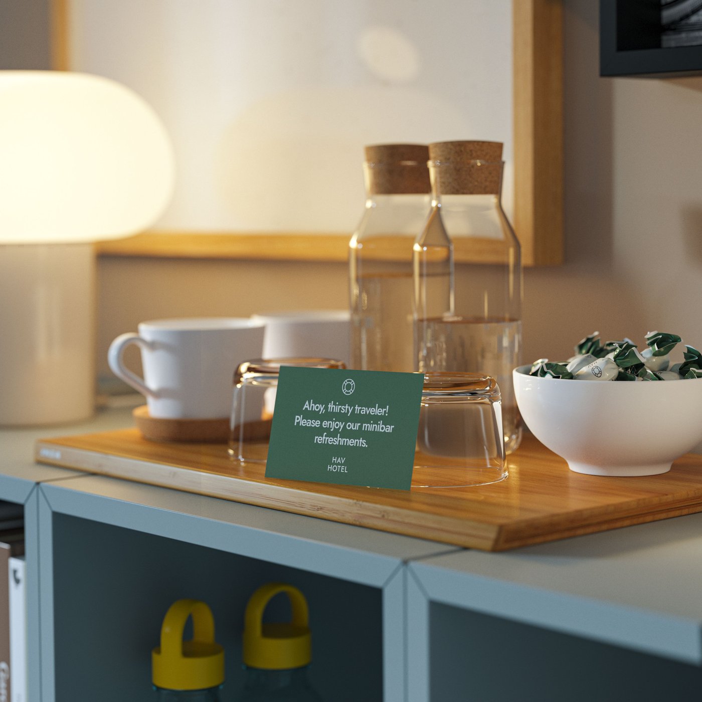 En minibar med IKEA 365+ glaskaraffer, vita muggar, glas och en godisskål på en skärbräda på EKET.
