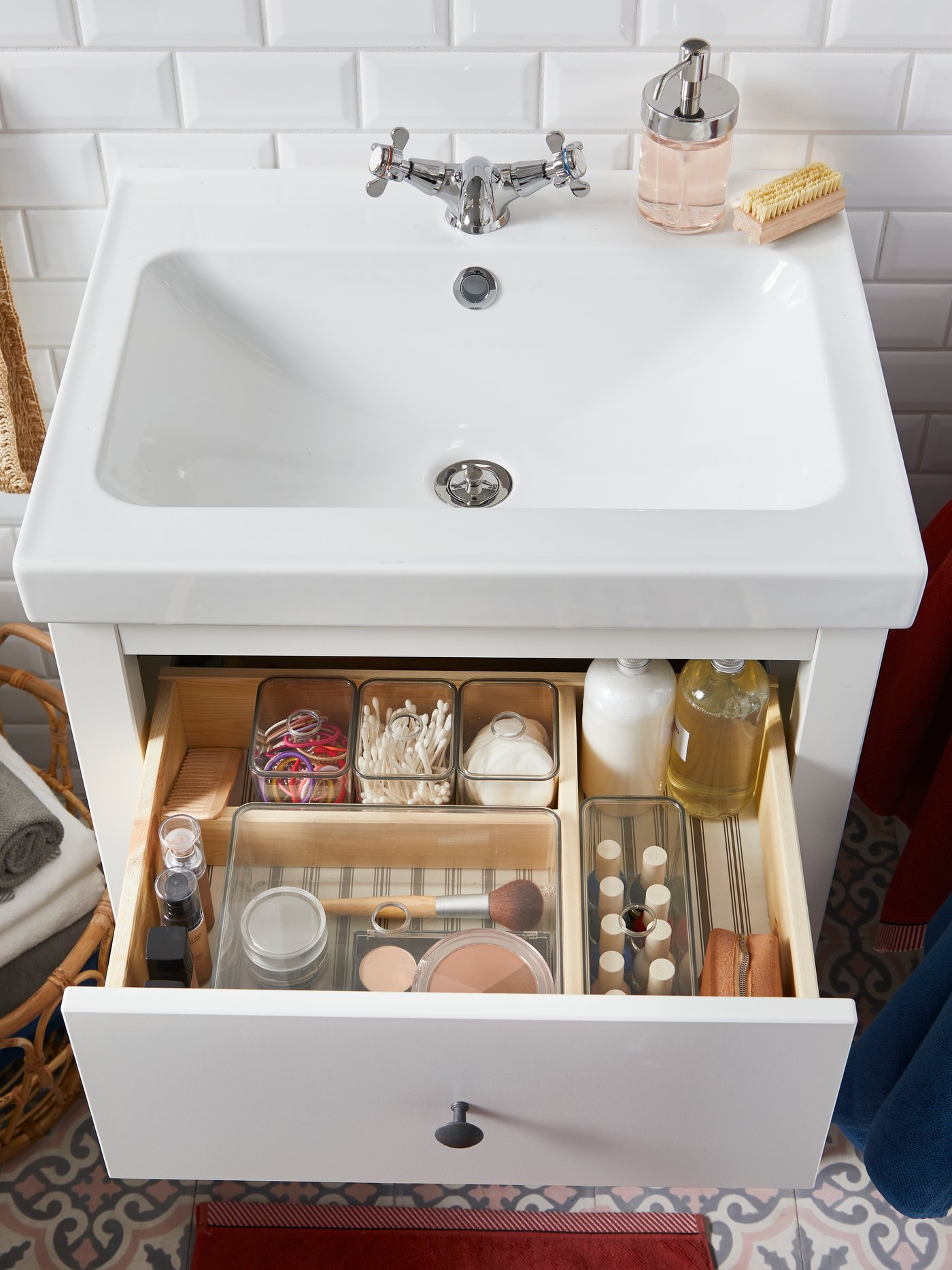 Biała szafka umywalkowa HEMNES z otwartą szuflad z kosmetykami.