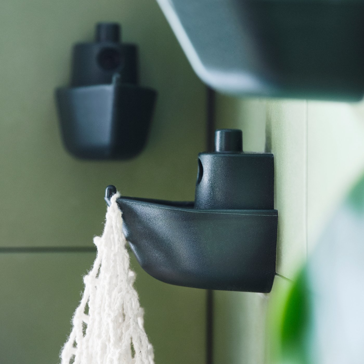 Three wall-mounted KNOPARE hooks mounted at different heights, one of which is holding a white macrame bag.