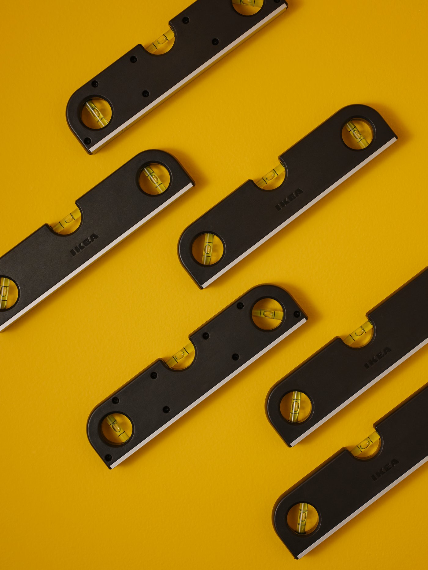 Six TRIXIG spirit levels neatly organised on a bright yellow surface.