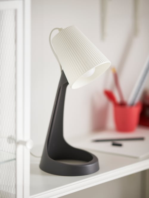 Modern workspace close-up of a grey work lamp made out of polypropylene plastic that provides a functional directed light.