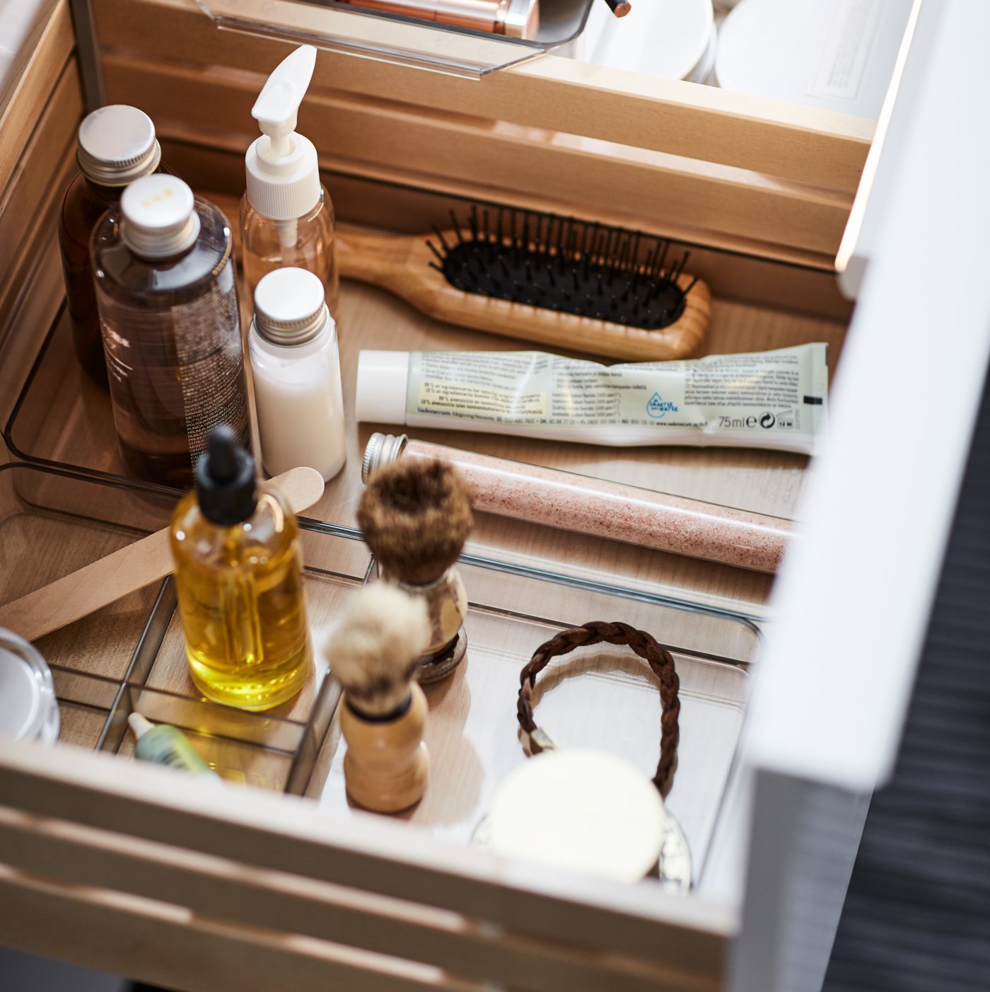 صورة مقربة لدرج مفتوح في حامل حوض GODMORGON، توجد به مستلزمات الحمام المعروضة بصورة مُرتَّبة.