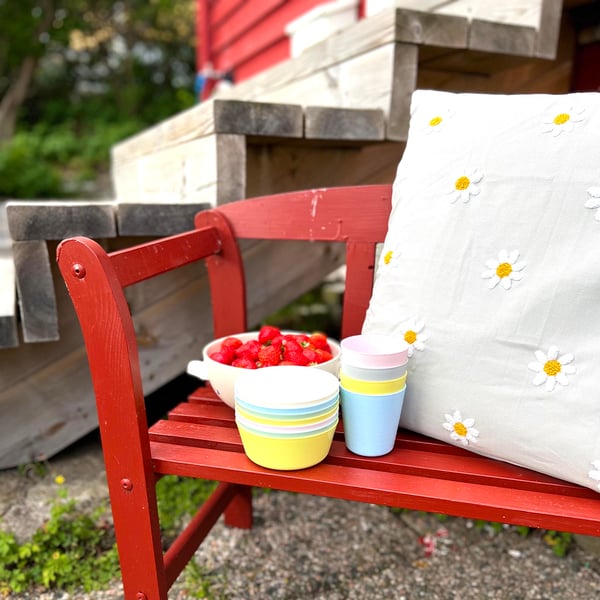 A red bench with KALAS bowls and cups on it.