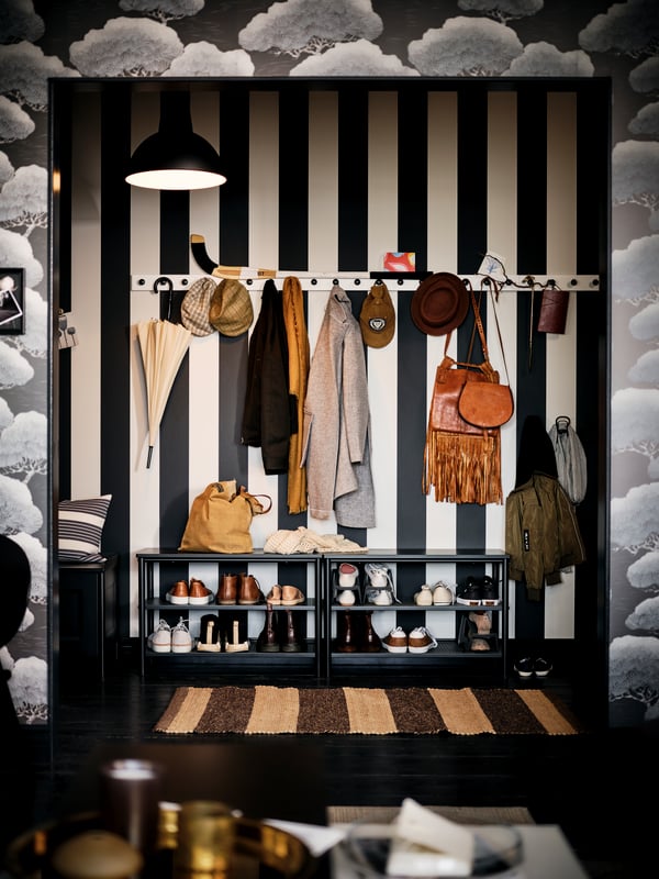 A kitchen with an artfully patterned wall opens onto a broad-striped, black-and-white hallway with two black PINNIG benches.