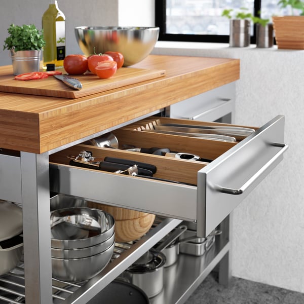 A white kitchen has a RIMFORSA kitchen island in silver and oak. 