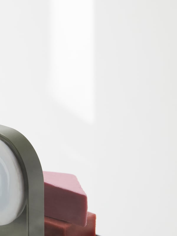 A rear view of a close-up of the corner of an ÖBONÄS wall shelf and two bars of soaps. A section of a larger image.