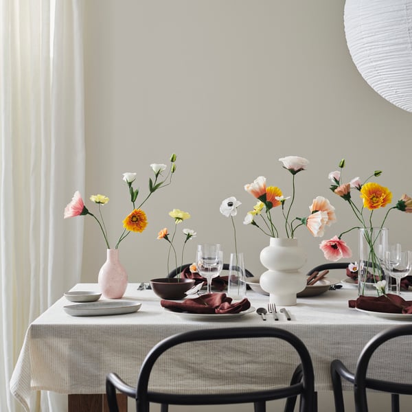 Ein Tisch ist mit verschiedenen Vasen und GULDSPETT Papierblumen dekoriert.