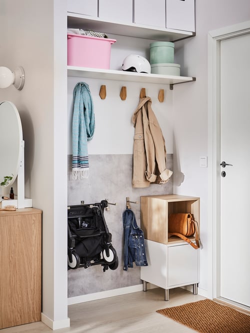 Hallway with clothes on hooks, shelf with storage boxes, wall panel, and a cabinet combination with legs on the floor.