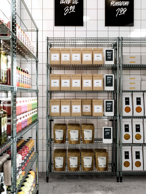 High OMAR open shelving units, stocked with food packages and bottles of juice. Blackboards with handwritten prices.