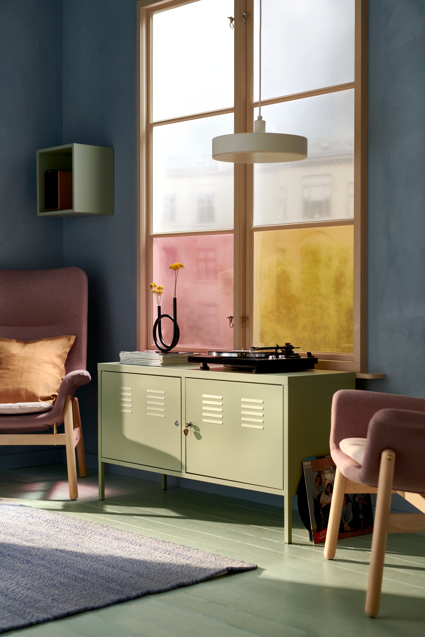 Ett vardagsrum med ett stort fönster. Bredvid fönstret står en rosa VEDBO fåtölj.