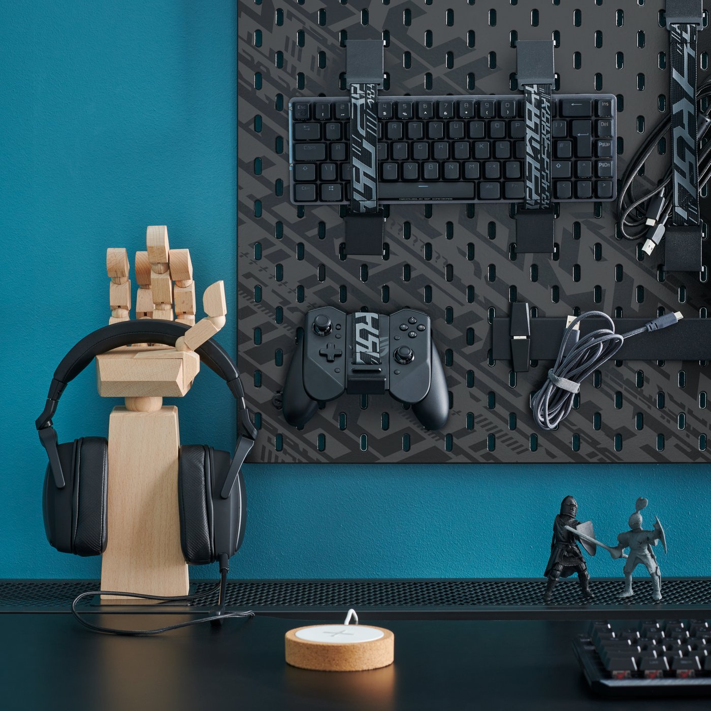 A LÅNESPELARE accessories stand shaped like a hand on a gaming desk against a blue wall in the home office.