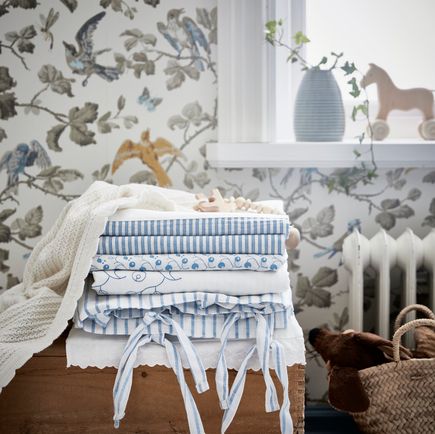 Une pile de linge de lit bleu et blanc dans une chambre de bébé.