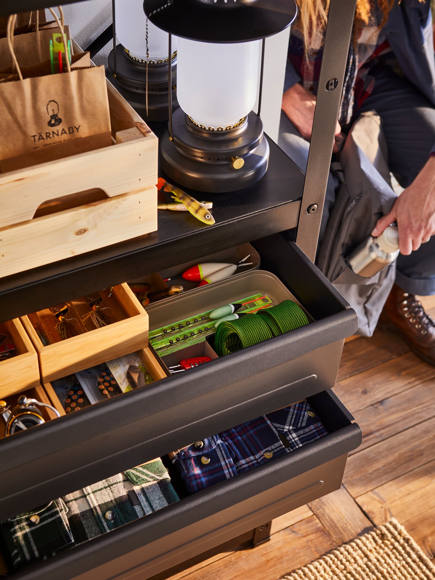 A black BROR shelving unit with drawers/shelves stands with open drawers containing various items including KNAGGLIG boxes.