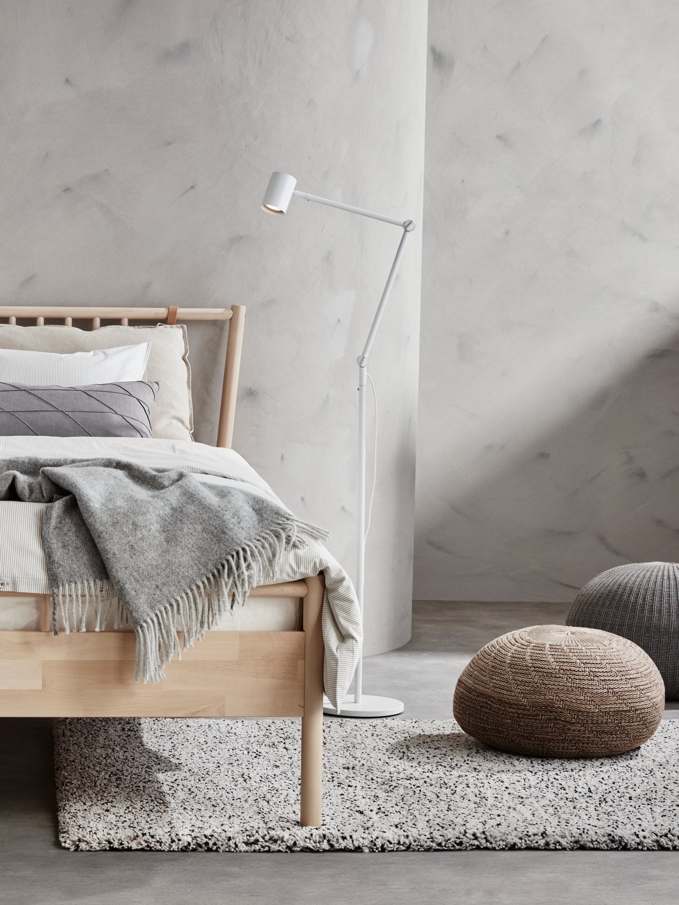 Sypialnia. Wnętrze w kolorach ziemi. Drewniane óko, pufa z naturalnych materiałów, koce i pledy.