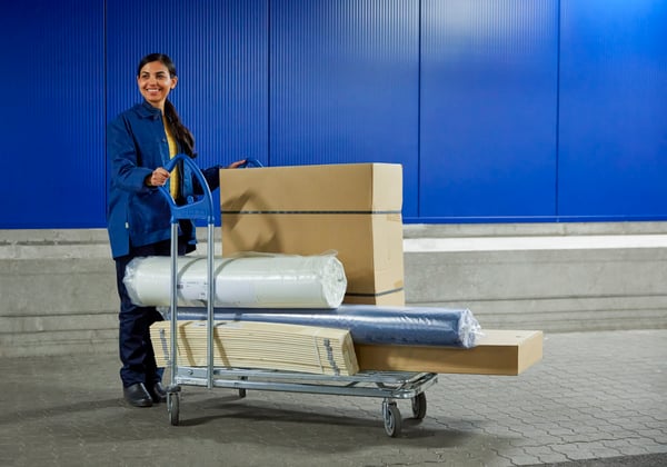 Eine IKEA Mitarbeiterin mit einem vollen Einkaufswagen.