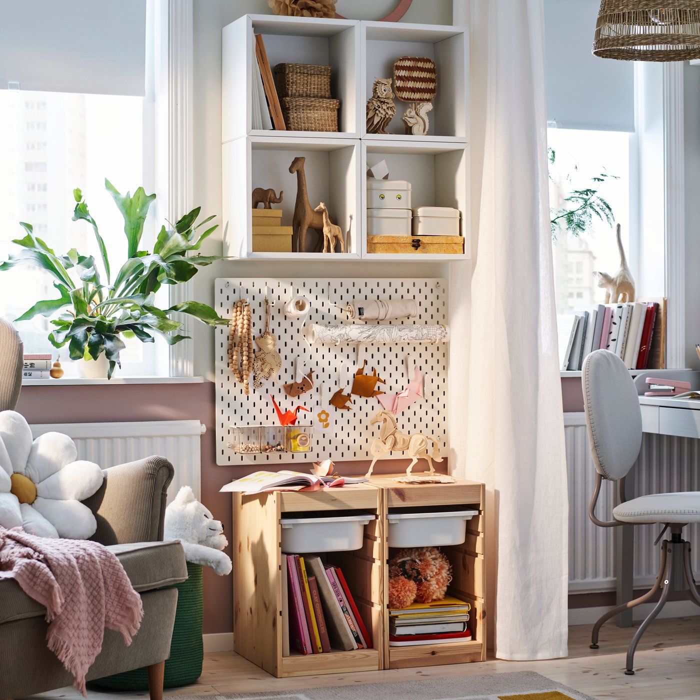 A bright bedroom with an EKET shelf and TROFAST storage against a wall and a SKÅDIS pegboard displaying art between them.