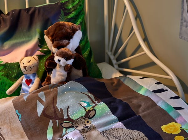Close-up on soft toys sitting in MINNEN extendable children’s bed made up with SKOGSDUVA bedding.