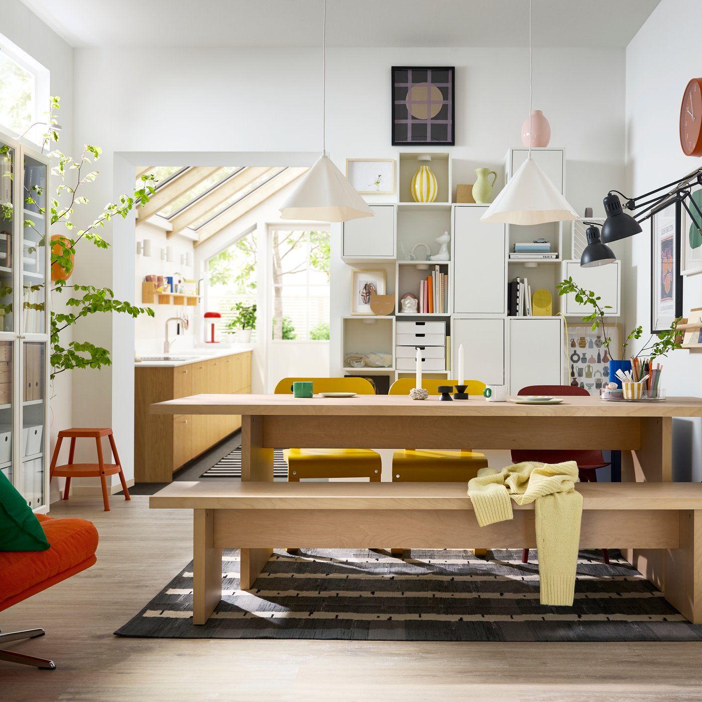 A bright dining room has a BERGSHYTTAN table with a bench in birch veneer on one side and colourful chairs on the other.