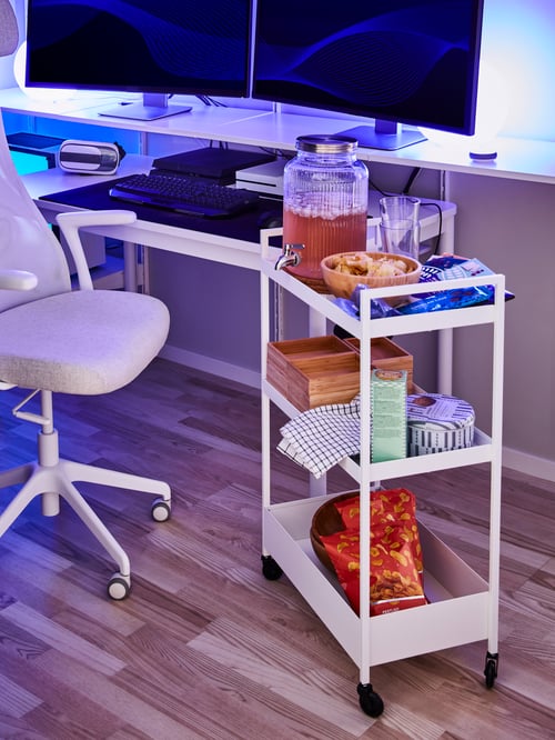 Workspace with a white trolley made out of steel supporting a white jar with tap next to an office chair with armrests.