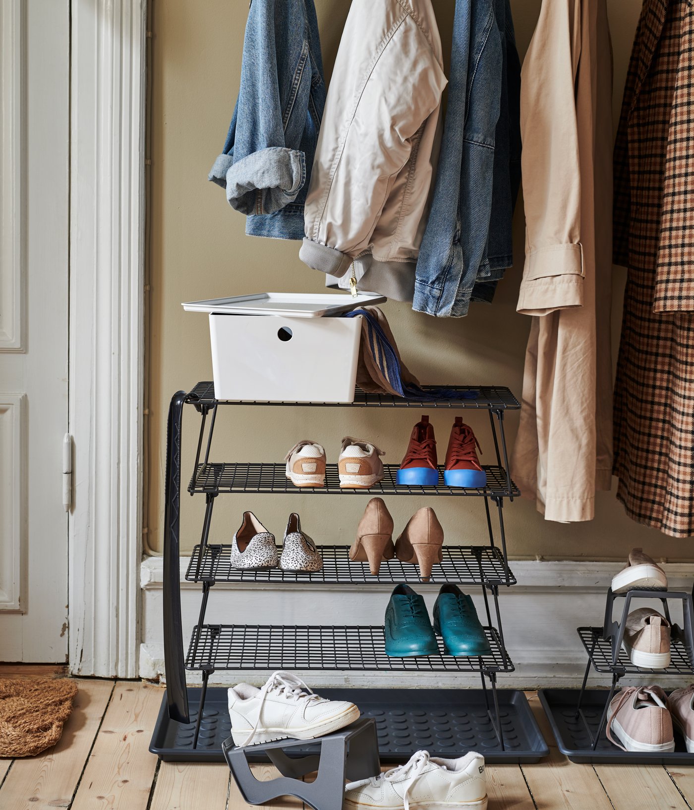 Een houten vloer met hangers aan de muur en een GREJIG schoenenrek