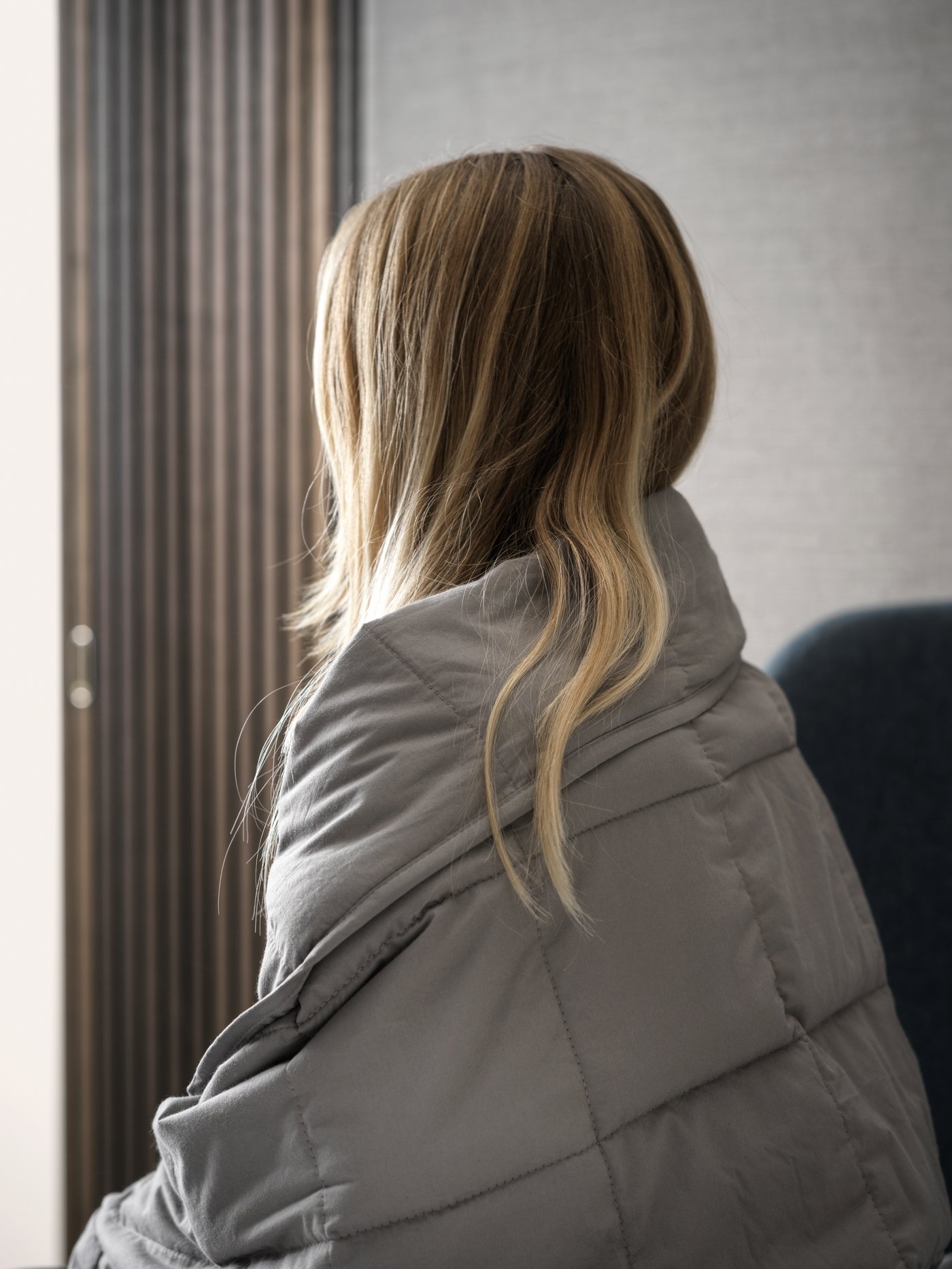 Eine Frau kuschelt sich in eine graue Gewichtsdecke.