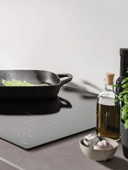Modern kitchen close-up of an elegant black induction hob with child lock underneath a black grill pan.
