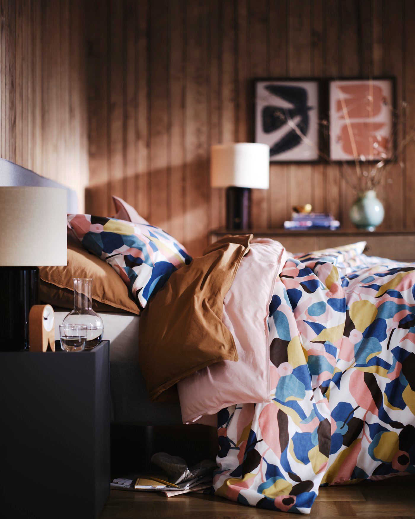 Une housse de couette VIDEOXBÄR blanche et multicolore ainsi que deux taies d'oreiller dans la chambre