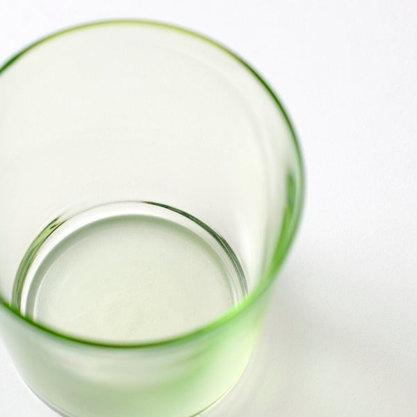 A green PAPPERSBJÖRK glass against a light grey surface.