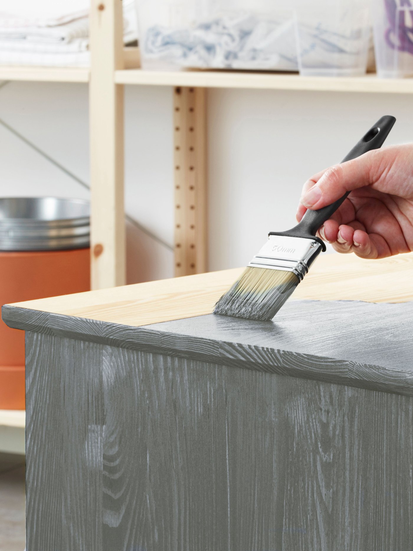 IVAR chair painted light green standing on old news papers in an empty room with light wooden floor and light pink walls.