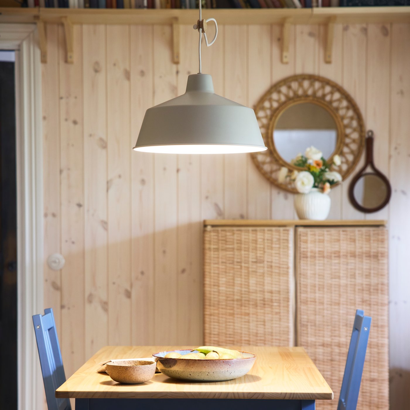 Lampa wisząca SJÖMAKT oświetla stół PINNTORP, na którym są miska GLADELIG i miska.