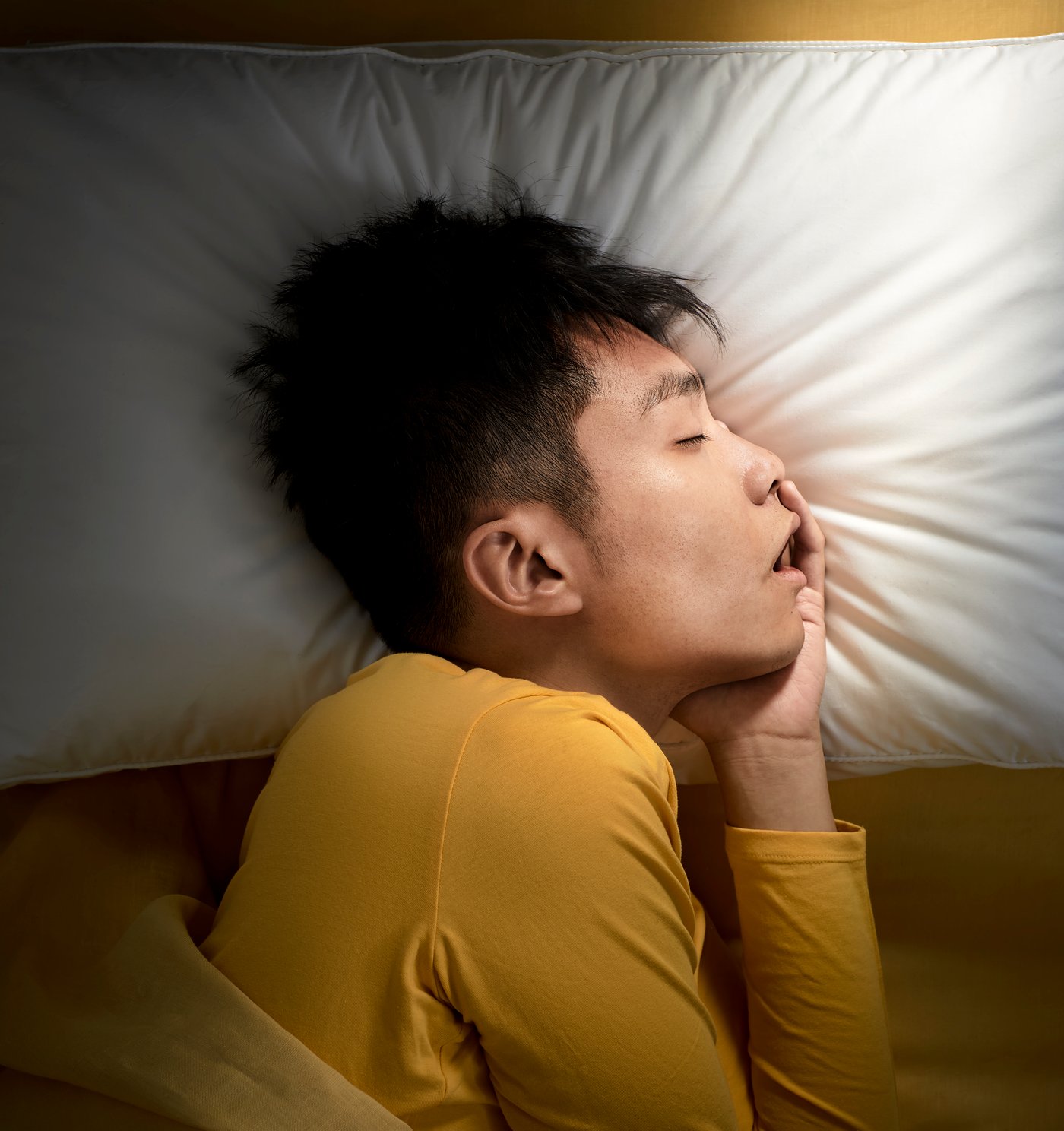 Un homme profondément endormi, sa tête reposant sur un oreiller ergonomique.