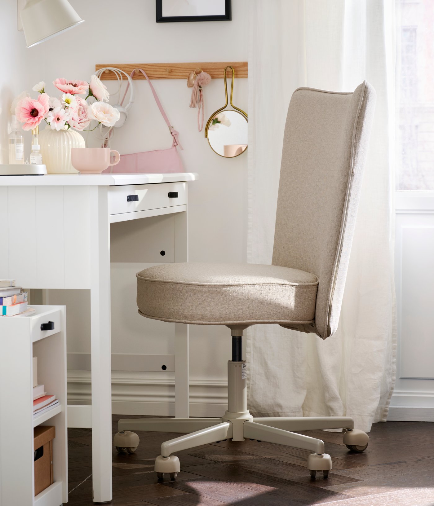 A home office with a beige BRYTNING swivel chair made from Naggen fabric, positioned near a white desk with flowers.