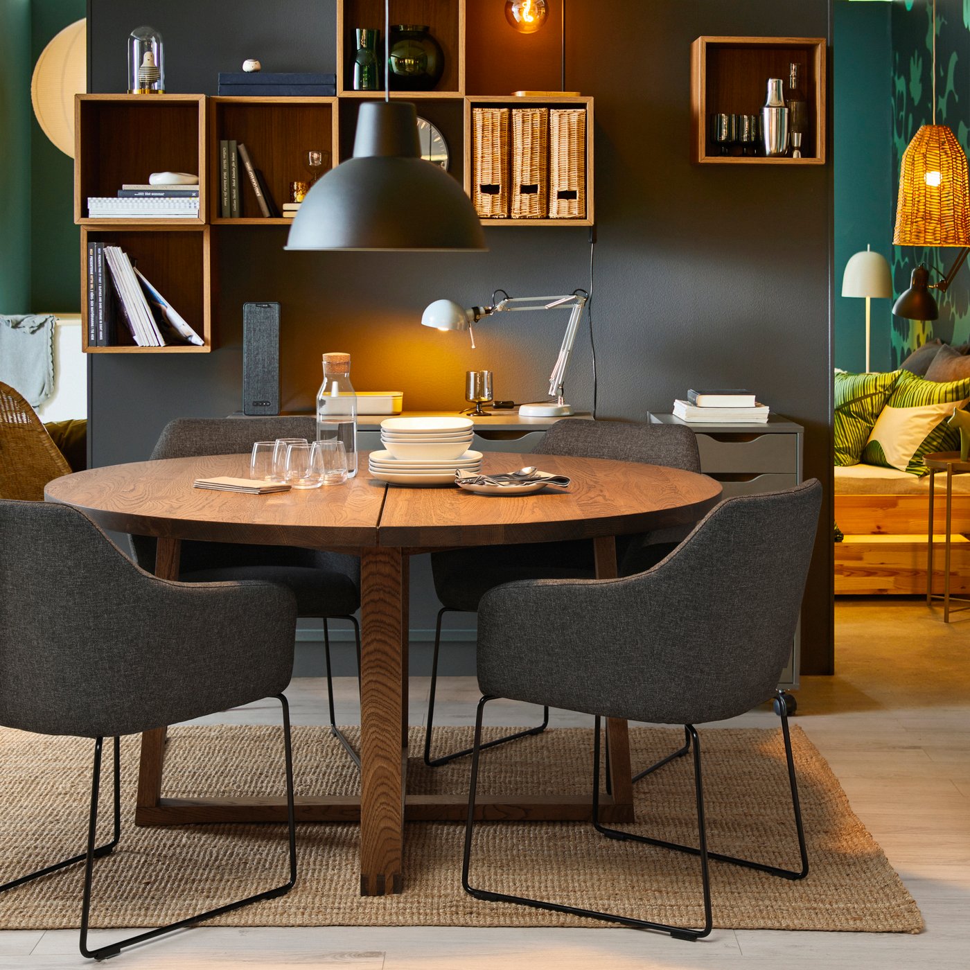 A round MÖRBYLÅNGA dining table surrounded by metal black/Gunnared dark grey TOSSBERG chairs with black legs.