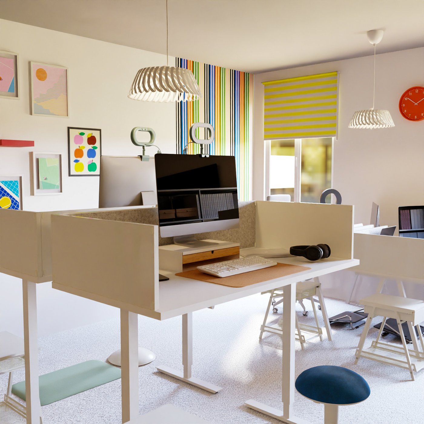 Teil eines Großraumbüros. Blick auf zwei sich gegenüberstehende hohe Schreibtische mit Hockern, darauf eine Tastatur und Monitor. Im Hintergrund an einer Wand Bilder und rechts davon ein Fenster. Neben den Schreibtischen weiter Arbeitsplätze.