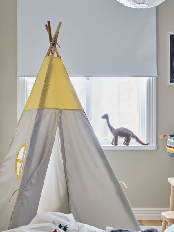 In einem Kinderzimmer steht ein kleines Zelt vor einem Fesnter. Auf dem Fesnterbrett steht ein kleiner DIno.