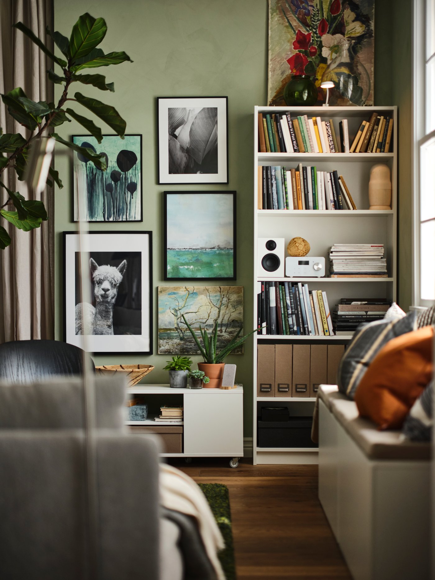 Living con una librería BILLY blanca con libros y un parlante, junto a una galería mural con obras de arte y fotografías.
