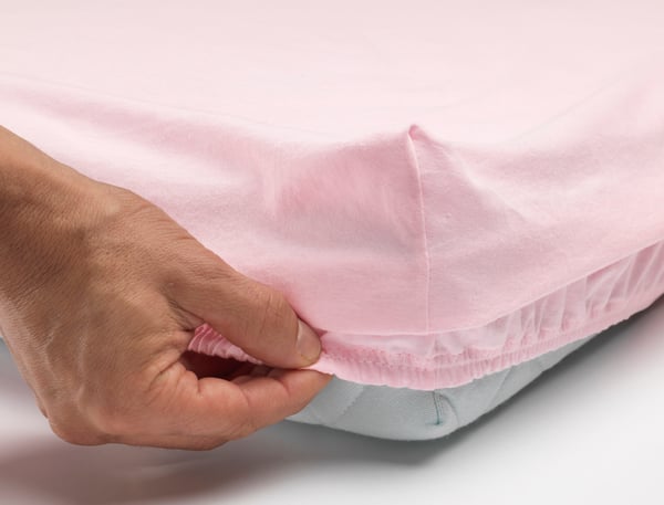 A white/pink LEN fitted sheet for cot