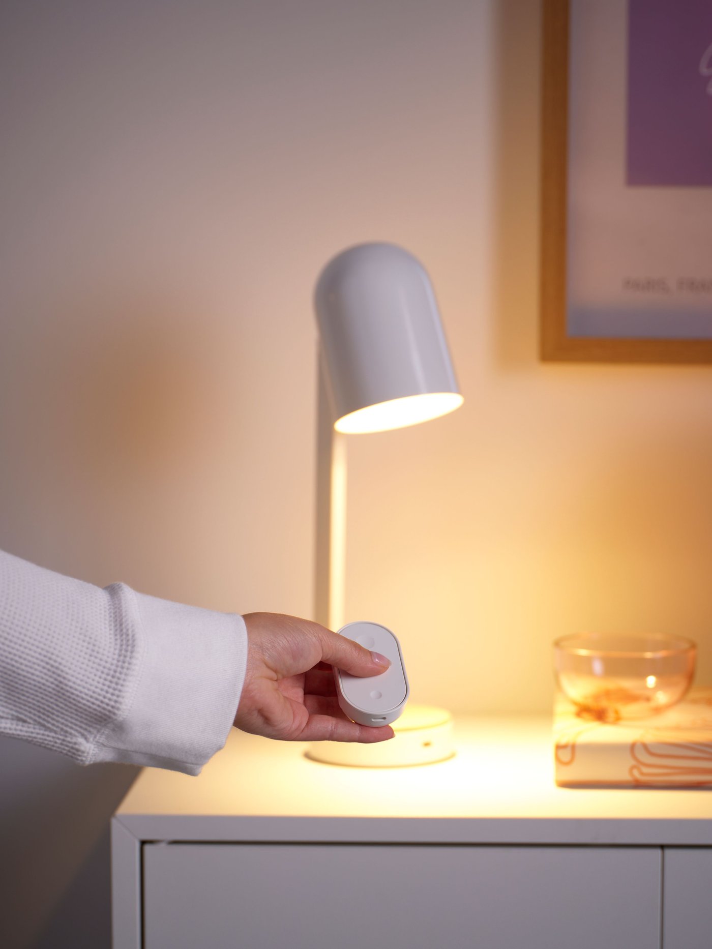 Someone is operating a white desk lamp using the smart KAJPLATS starter kit.