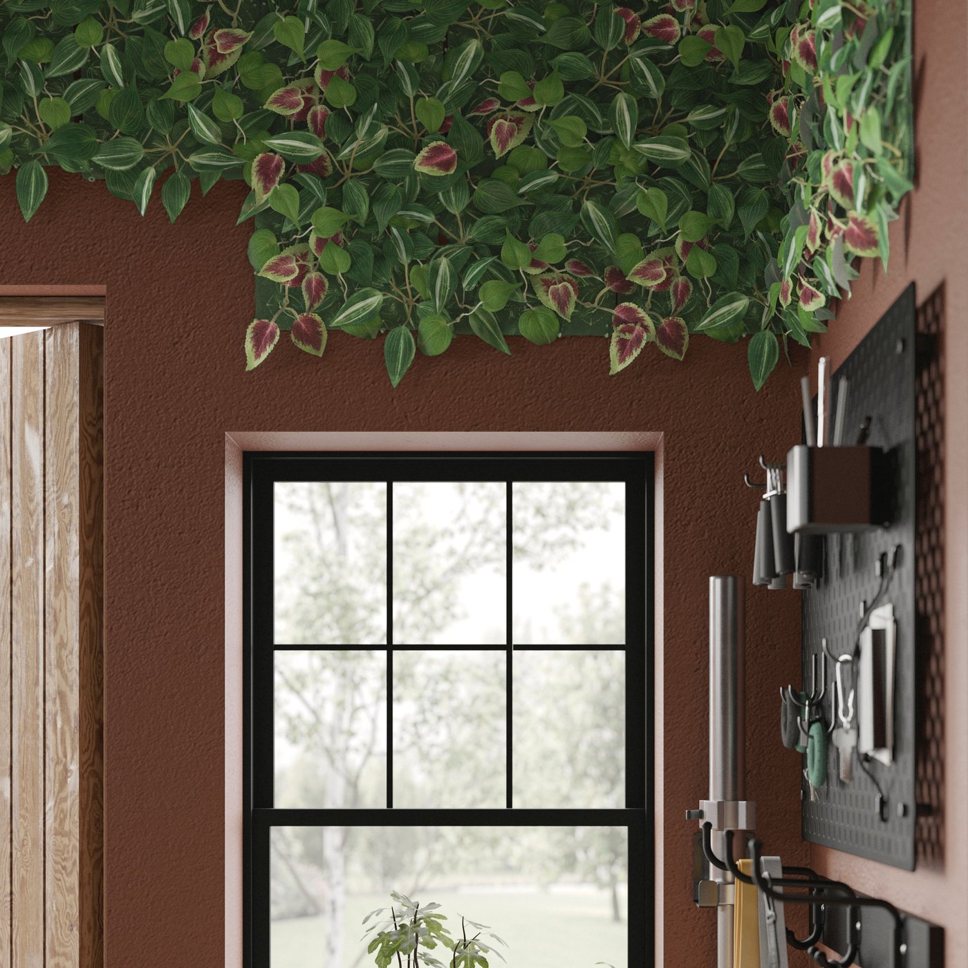 A corner with part of the ceiling covered with FEJKA artificial plants, next to gardening tools arranged on the wall.