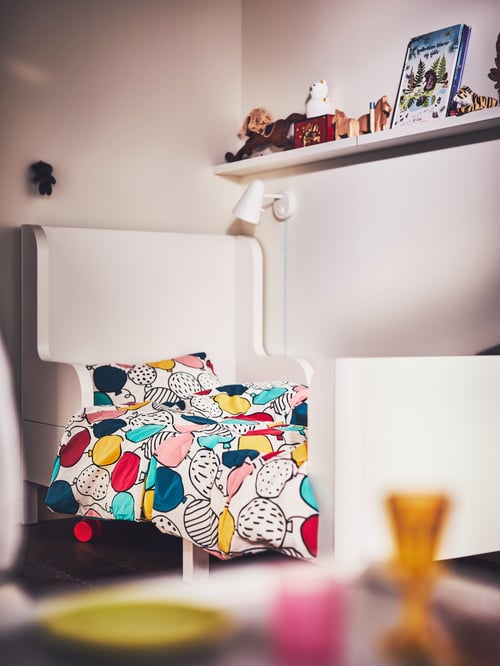 Children’s bedroom with white extendable bed frame and colourful cotton duvet cover and pillowcase set with balloon pattern.