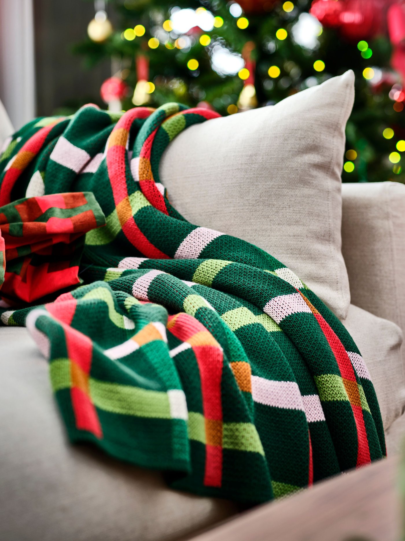 Un plaid multicolore VINTERFINT est drapé sur un canapé beige.