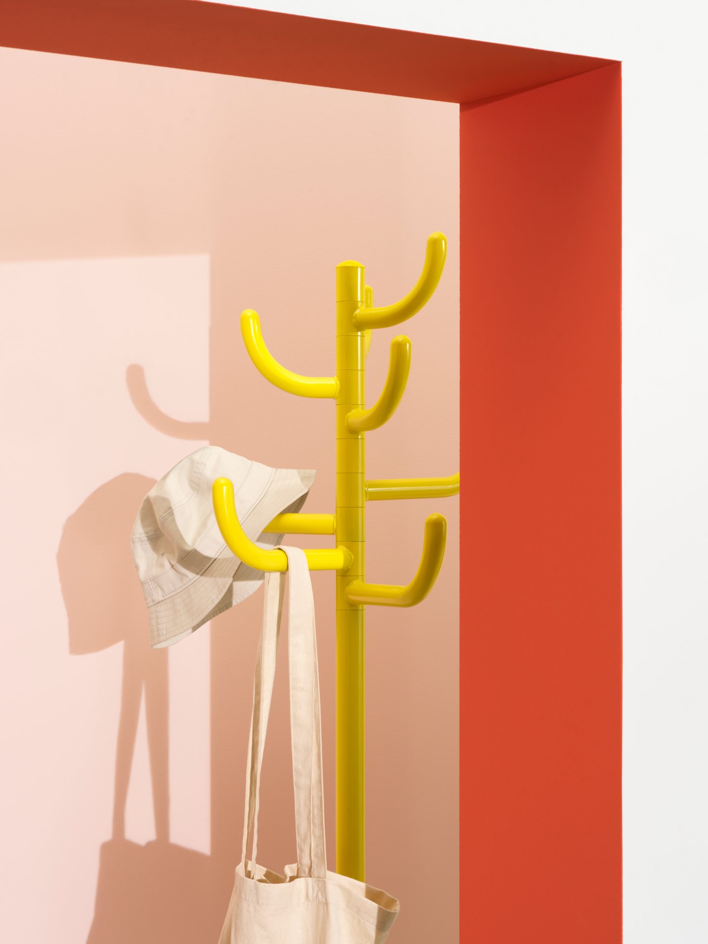 A white canvas bag and bucket hat hang from the tree-like arms of a yellow BONDSKÄRET coat/hat stand in a bright space.
