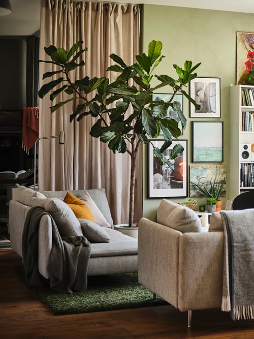 Ein offener Wohn- und Essbereich mit zwei beigebraunen SÖDERHAMN 3er-Sofas, weißen BILLY Bücherregalen und einer Galeriewand.
