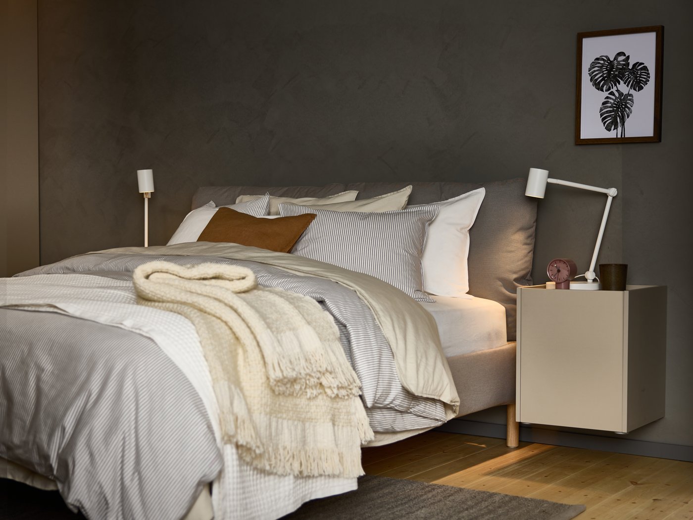 Una cama llena de textiles en un dormitorio de color gris