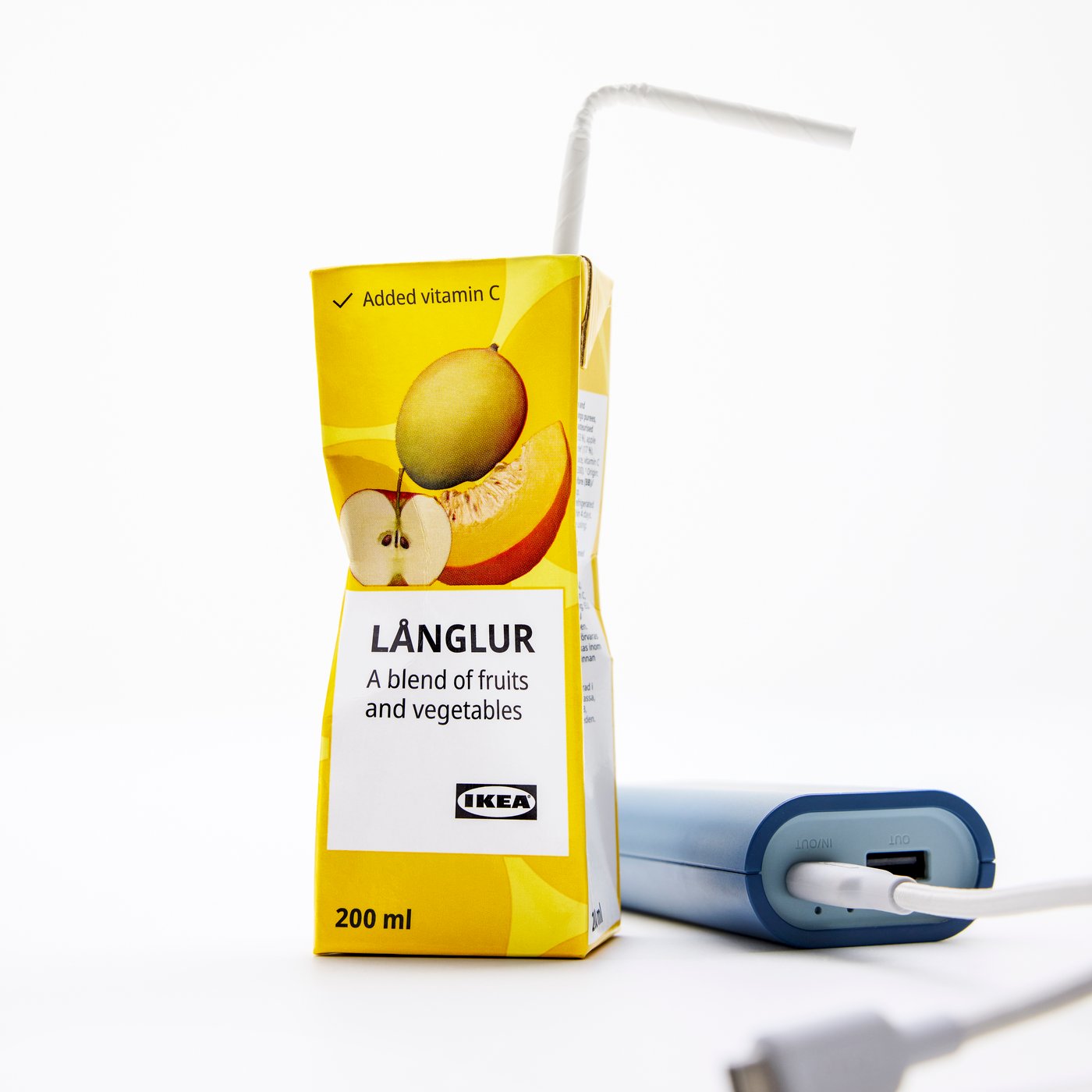 En förpackning med LÅNGLUR frukt- och grönsakssmoothie. Bredvid ligger en powerbank och en mobilladdare.